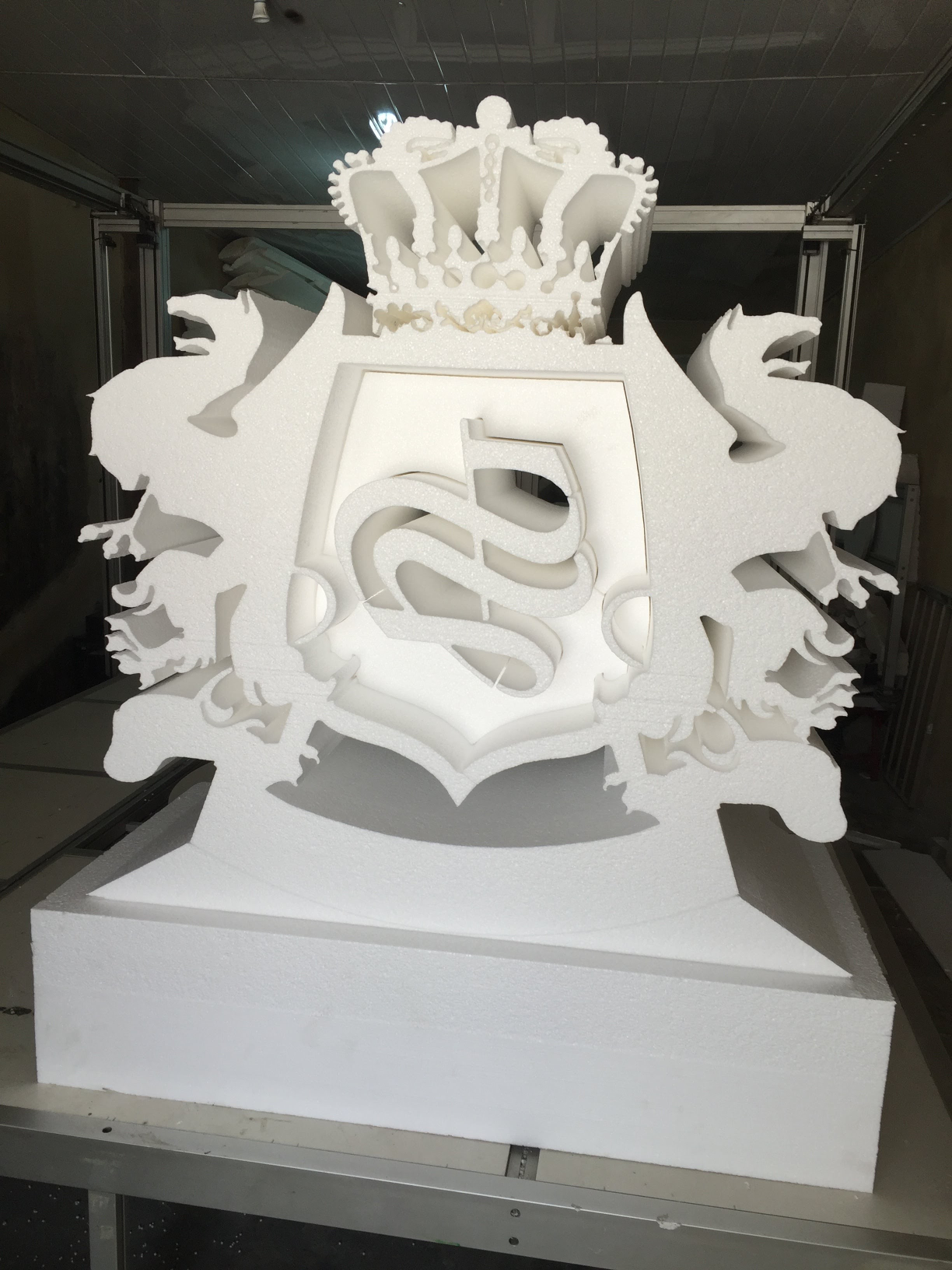 Sculpted white decorative crest with a crown and central monogram